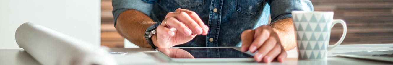 man working on tablet drinking coffee